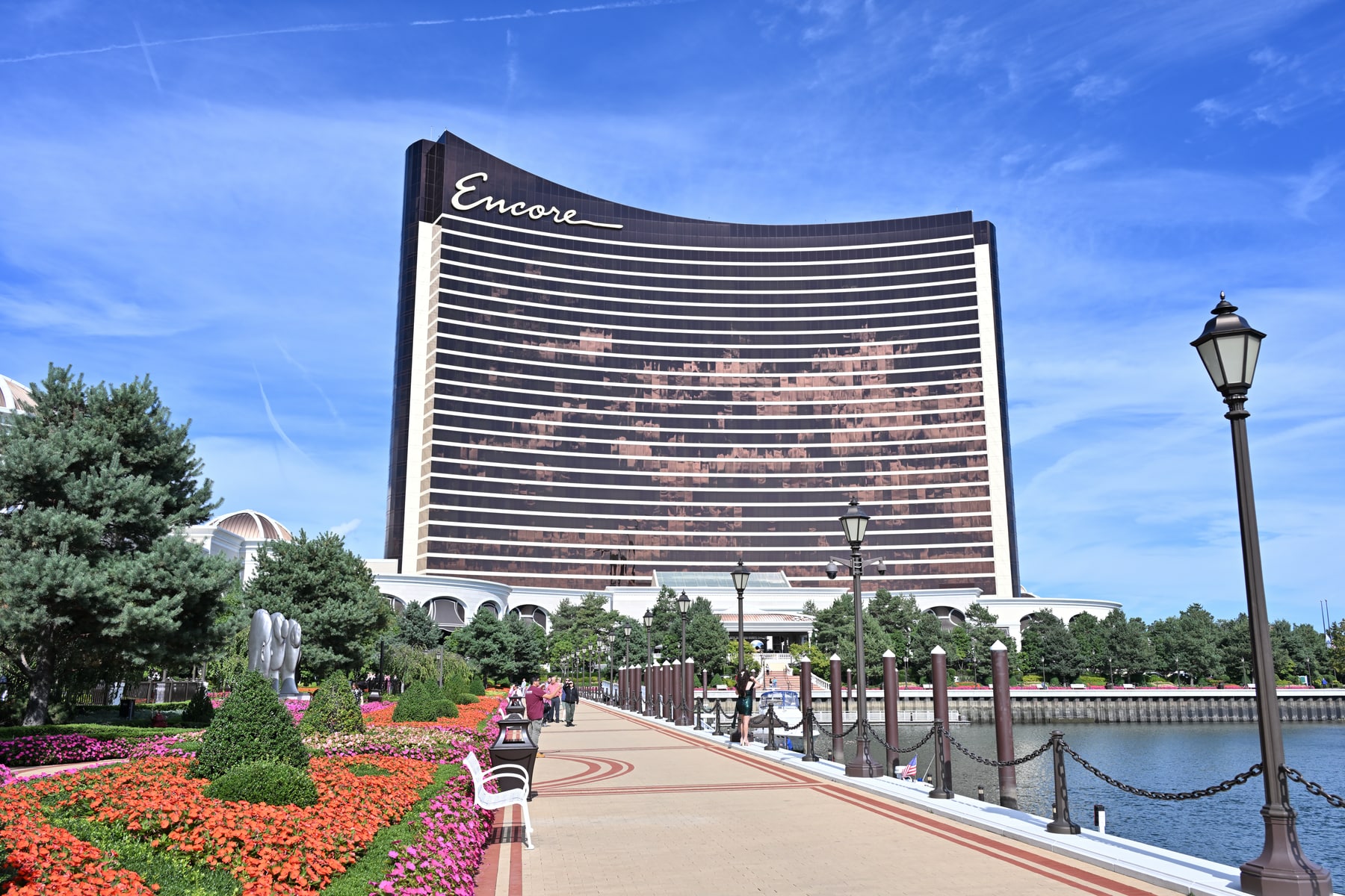 Encore Boston Harbor casino and hotel overlooking its landscaped riverwalk, with the Encore sign clearly visible